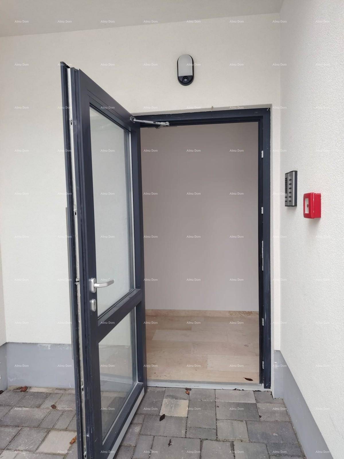 Moderner Hauseingang mit Glastür und Gegensprechanlage, führt in einen hellen Innenraum.