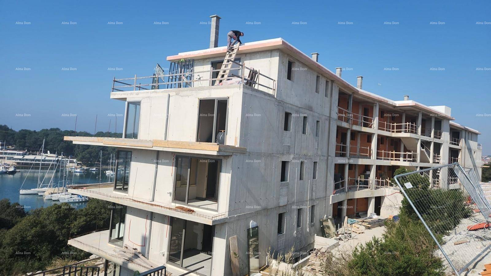 Mehrstöckiges Neubaugebäude im Bau mit einem Arbeiter auf dem Dach und Blick auf den Yachthafen.