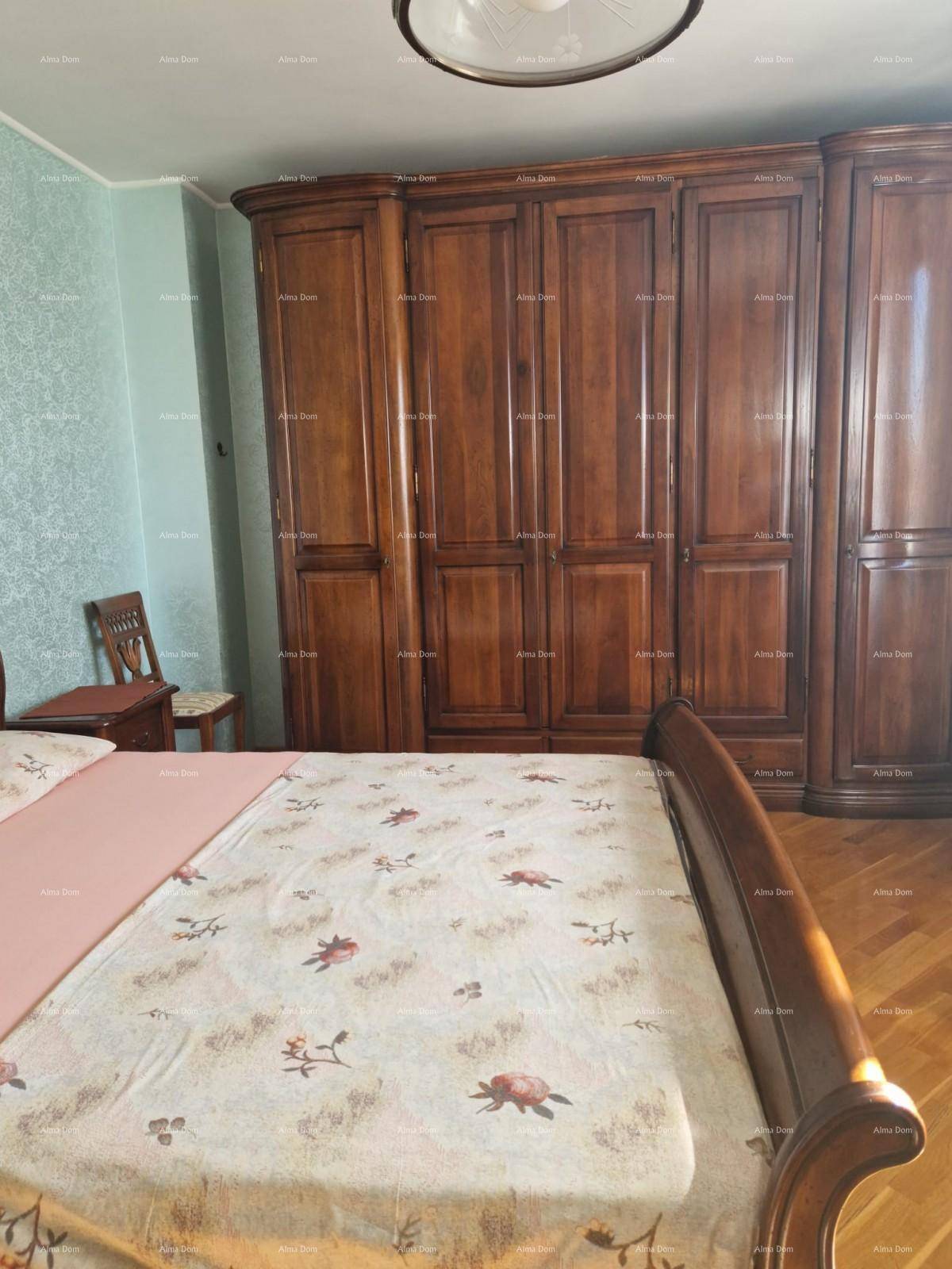 Schlafzimmer mit großem Holzkleiderschrank, Parkettboden und floral gemustertem Bett.