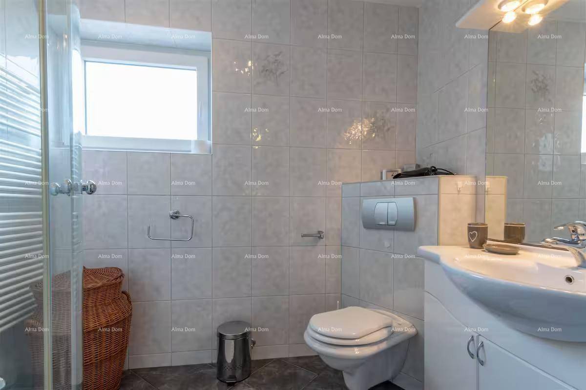 Helles Badezimmer mit Toilette, Waschbecken, Duschbereich und Fenster.
