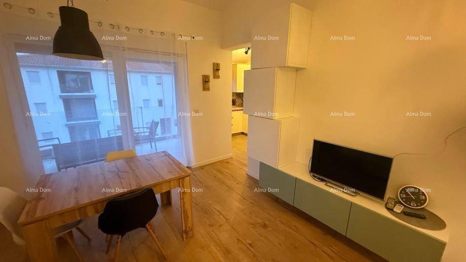 Wohnbereich mit Fernseher, Esstisch und großem Fenster mit Zugang zum Balkon.