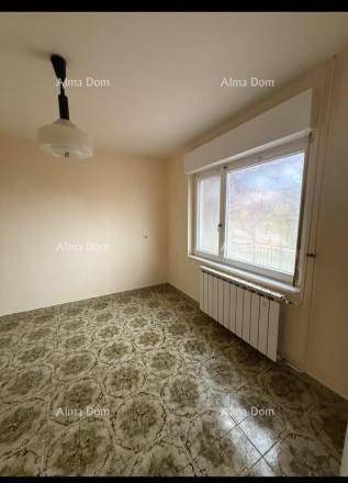 Leeres Zimmer mit gemusterten Fliesen, beigen Wänden und Fenster mit Heizkörper.