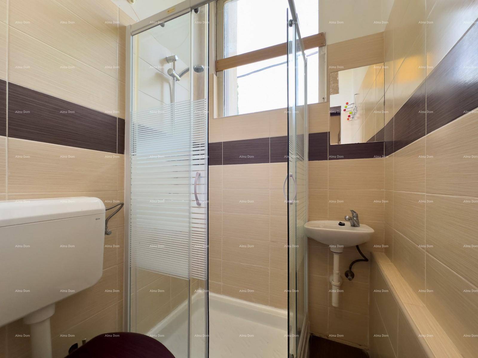 Kleines Badezimmer mit Duschkabine, WC und Waschbecken in beigen Fliesen.