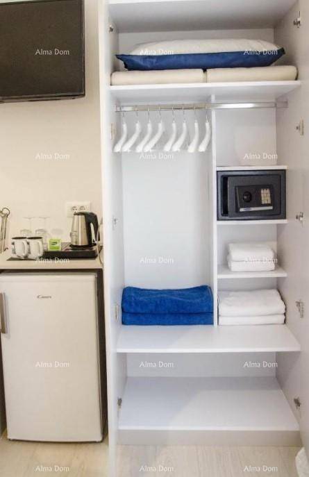 Offener Kleiderschrank mit Regalen, Kleiderbügeln und einem Safe, daneben eine Minibar und Kaffeestation.