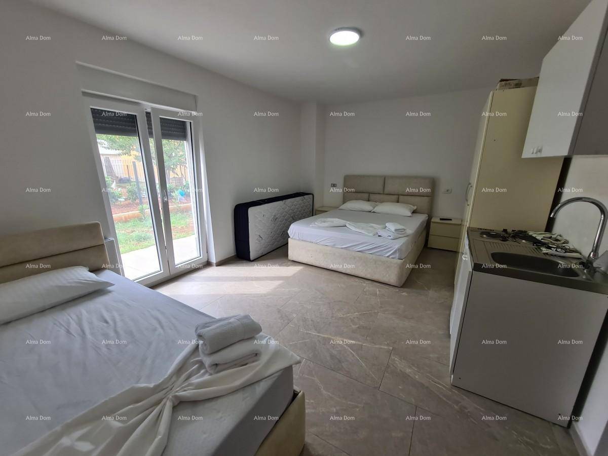 Geräumiges Schlafzimmer mit zwei Betten, kleiner Küchenzeile und Zugang zum Garten.
