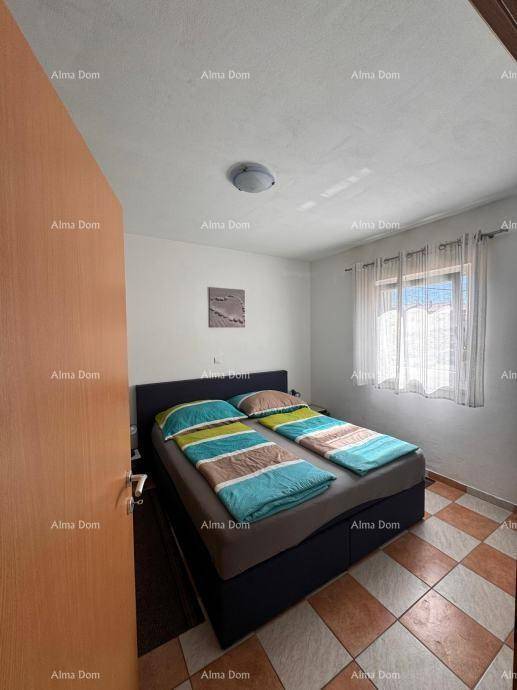 Schlafzimmer mit Doppelbett, blauer Bettwäsche und einem Fenster, das Tageslicht hereinlässt.
