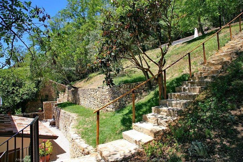 Steintreppe führt durch einen terrassierten Garten mit Trockenmauern und Bäumen.