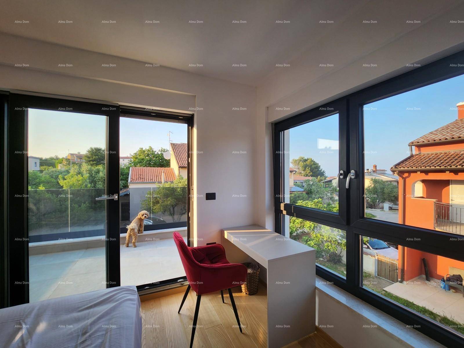 Helles Schlafzimmer mit Schreibtisch, rotem Stuhl und Zugang zu einem Balkon mit Blick auf die Umgebung.