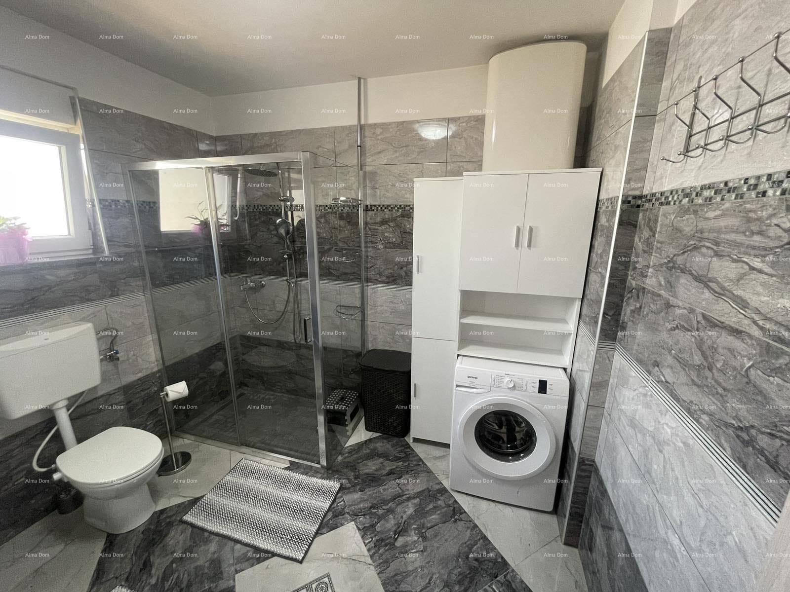 Modernes Badezimmer mit grauen Fliesen, einer Duschkabine, Toilette und Waschmaschine.