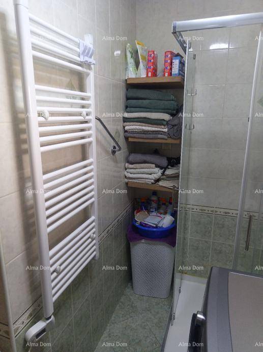 Badezimmer mit Duschkabine, Handtuchheizkörper und praktischen Regalen für Handtücher.