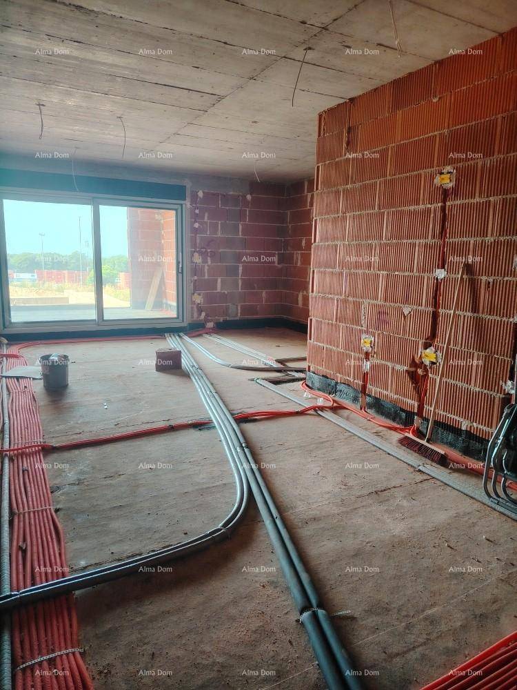 Innenraum im Rohbau mit Ziegelwänden, Betonboden und einer großen Schiebetür, die nach außen führt.