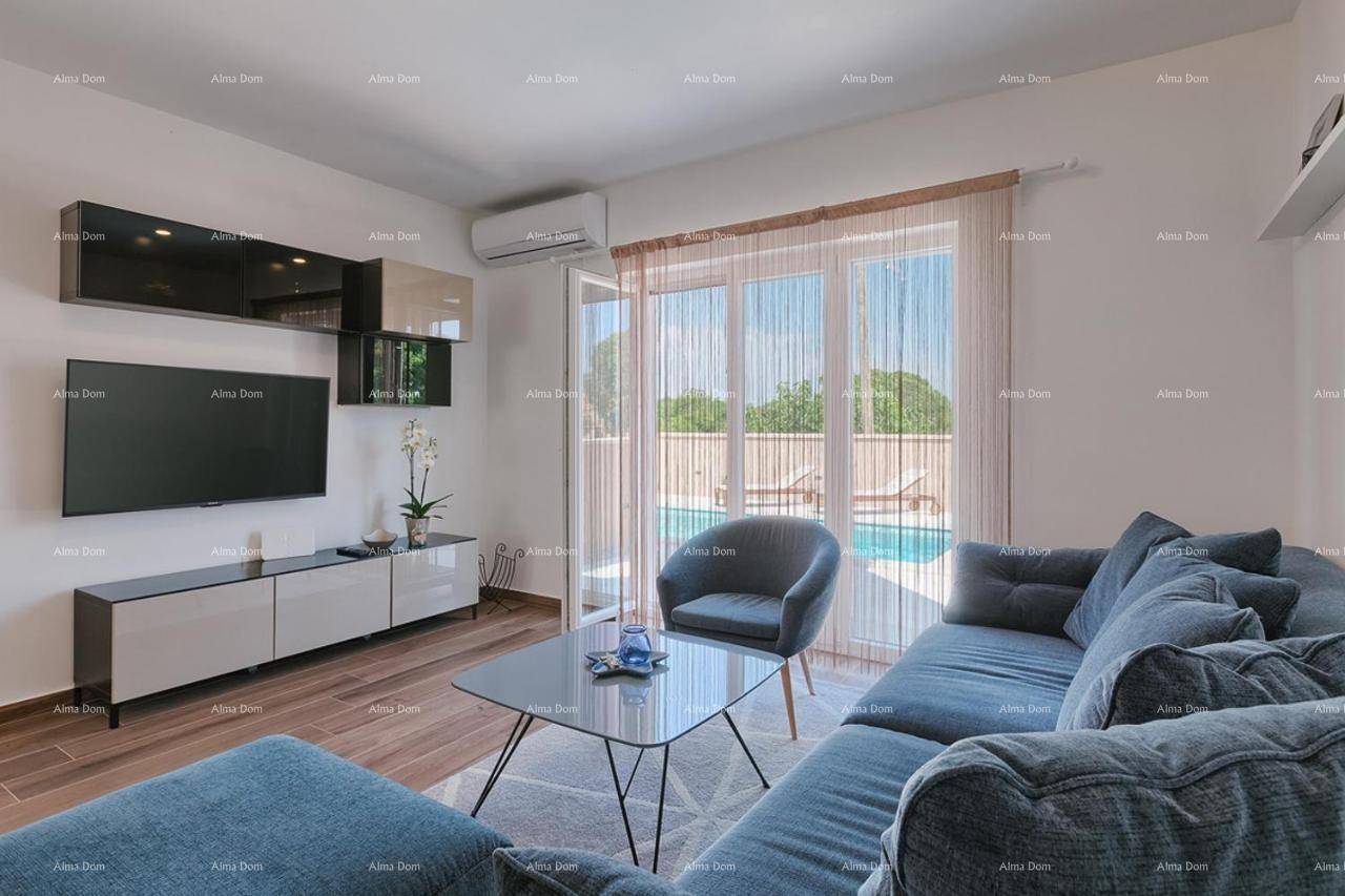 Modernes Wohnzimmer mit bequemer blauer Couch, Fernseher und Blick auf den Poolbereich.