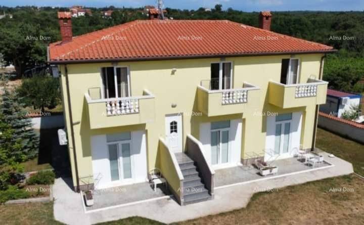 Gelbes Haus mit rotem Ziegeldach, mehreren Balkonen und Terrassen im Erdgeschoss.