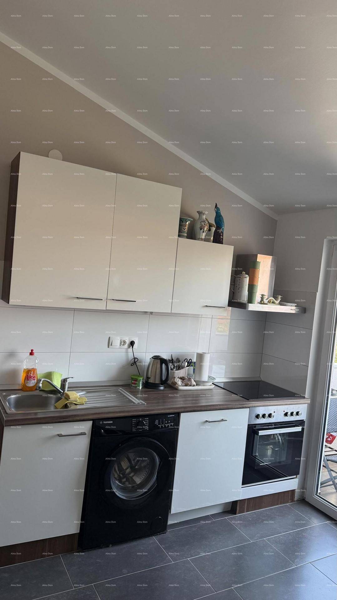 Kompakte Küchenzeile mit integrierter Waschmaschine, Kochfeld und Backofen unter einer Dachschräge.