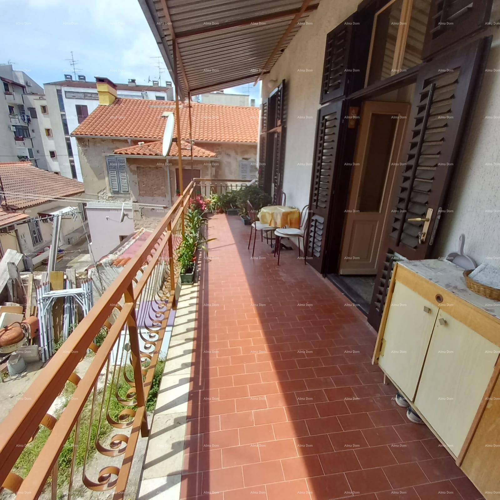 Langer Balkon mit Fliesenboden, Sitzgelegenheiten und Blick auf die Umgebung.
