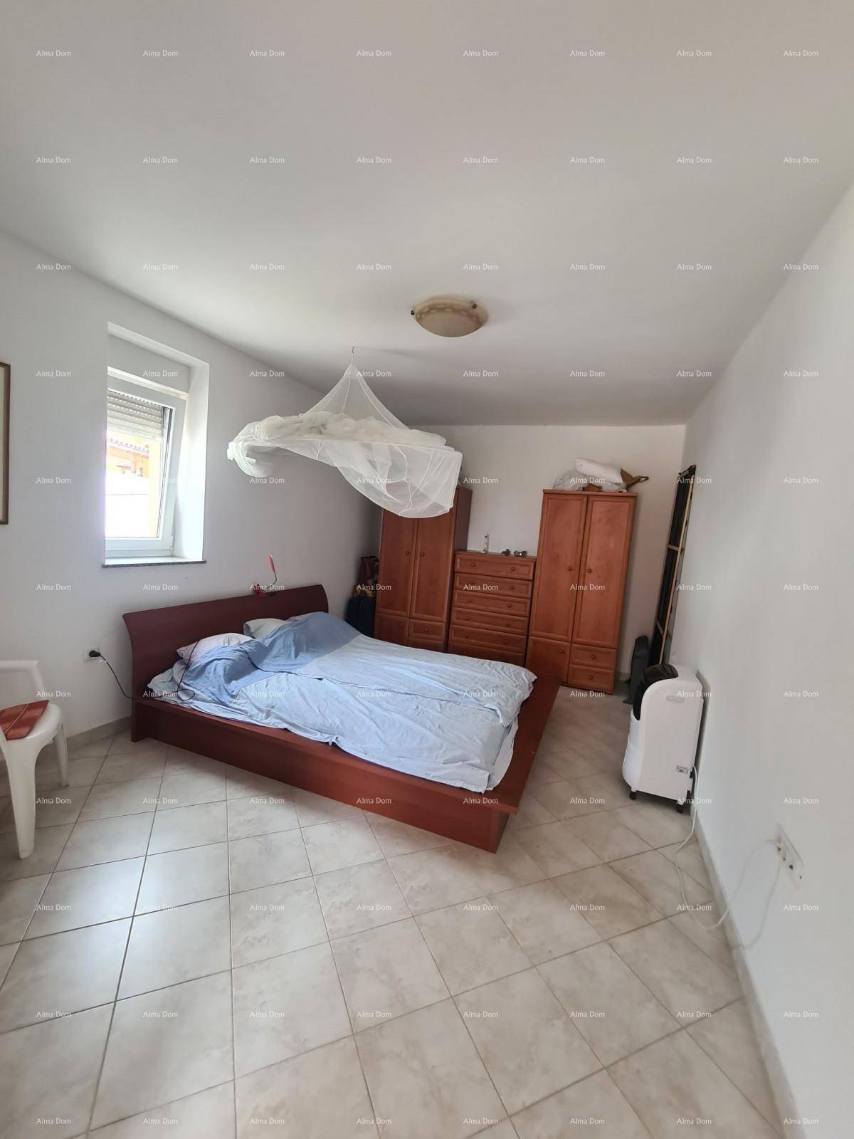 Schlafzimmer mit Doppelbett, Holzmöbeln und Fliesenboden, gut beleuchtet durch ein Fenster.