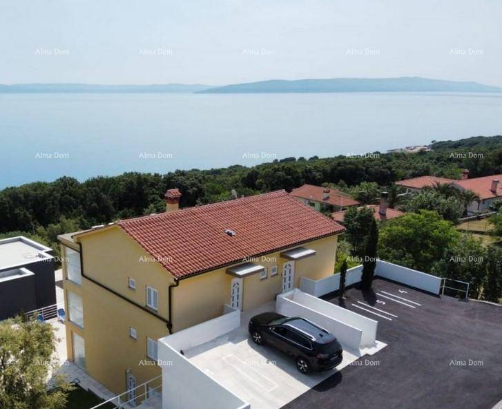 Apartmentgebäude mit Parkplätzen und weitem Blick auf das Meer und die umliegende Landschaft.