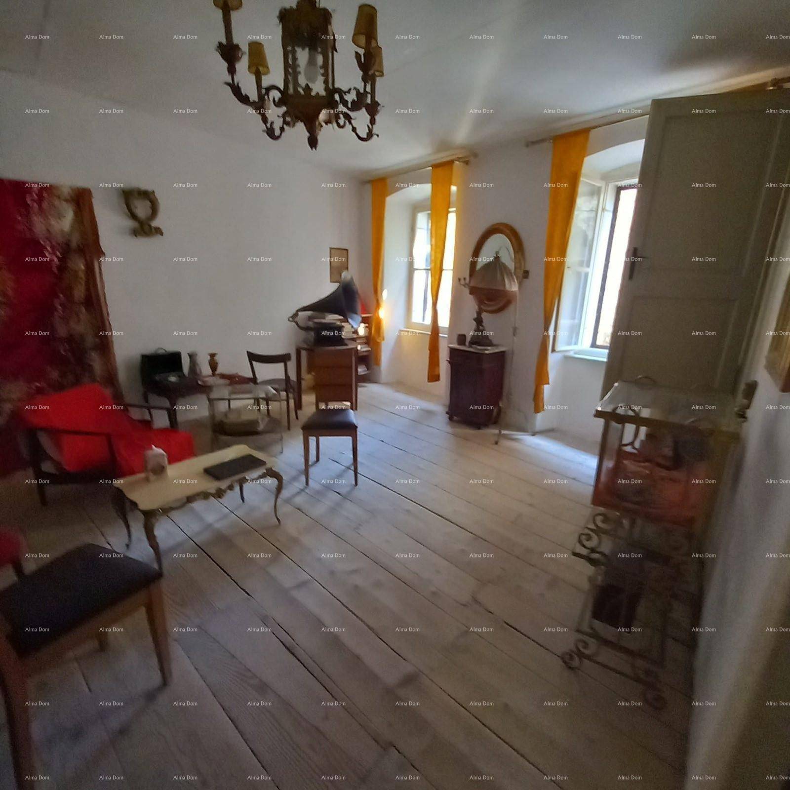 Helles Wohnzimmer mit Holzdielenboden, Kronleuchter und gelben Vorhängen an den Fenstern.
