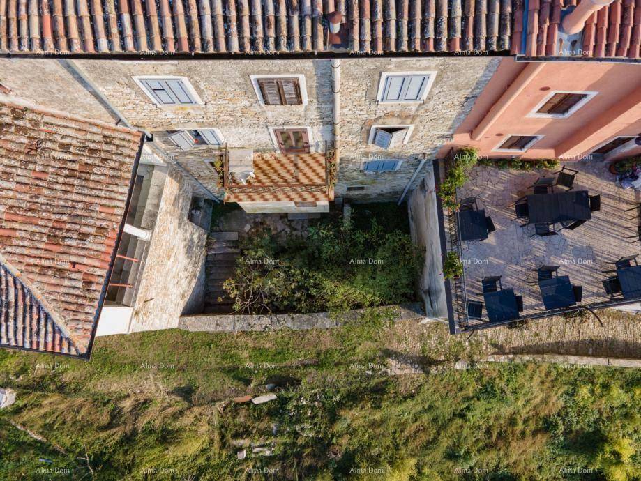 Blick von oben auf einen Innenhof mit gepflasterter Terrasse und Sitzgelegenheiten zwischen alten Gebäuden.