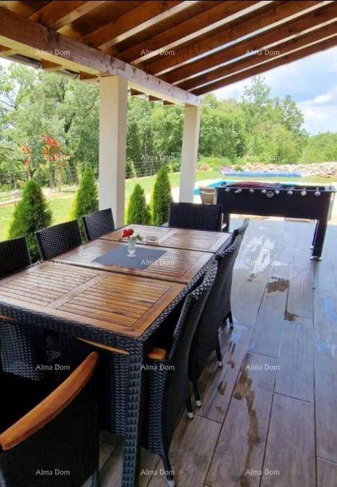 Überdachte Terrasse mit Esstisch, Stühlen und Tischfußball, Blick auf den Pool und die Natur.