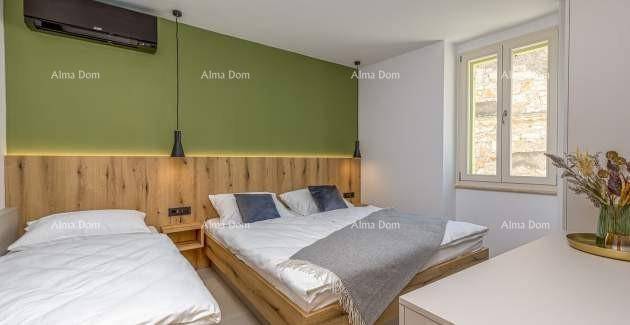 Helles Schlafzimmer mit Doppelbett, Einzelbett, grüner Akzentwand und Klimaanlage.