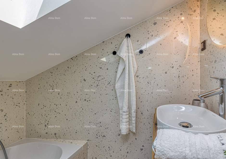 Helles Badezimmer mit Dachschräge, modernem Waschbecken und gemusterten Fliesen.