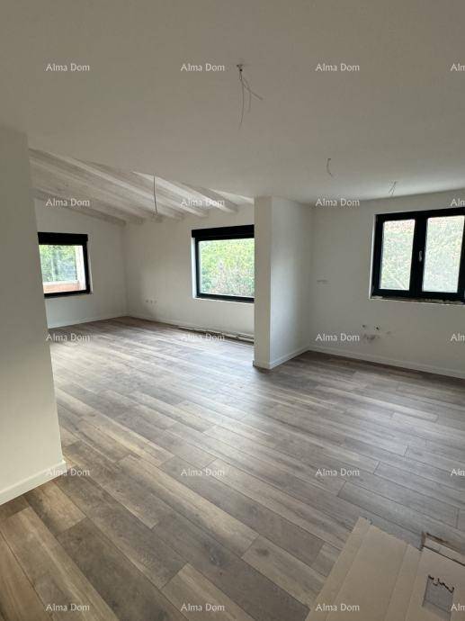 Heller Wohnraum im Dachgeschoss mit Holzbalken, großen Fenstern und Holzboden.
