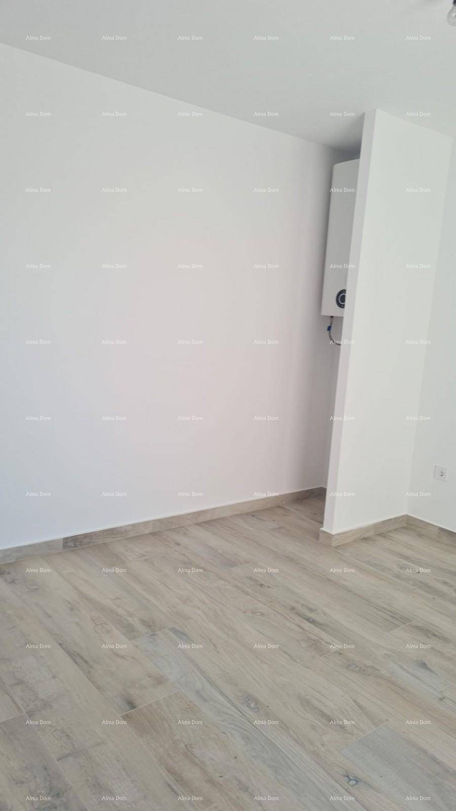 Leerer Raum mit Holzboden, weißen Wänden und einem sichtbaren Warmwasserbereiter.