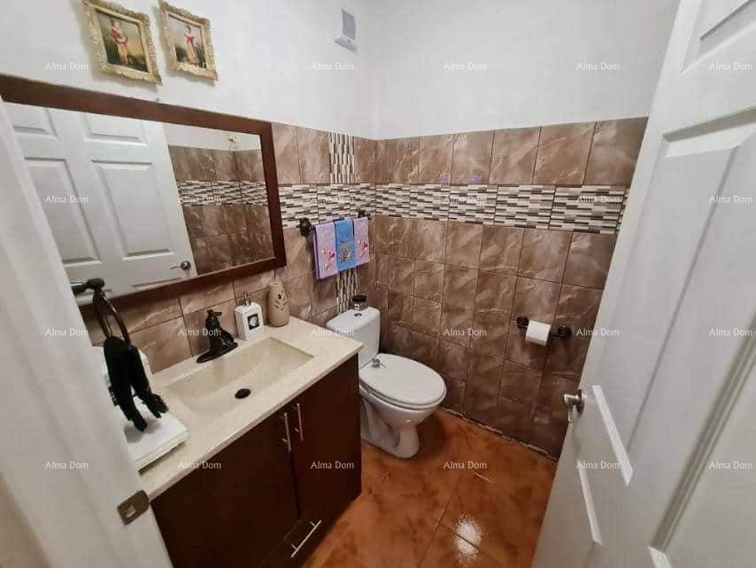 Modern gefliestes Badezimmer mit Einzelwaschbecken, Toilette und Wandspiegel.