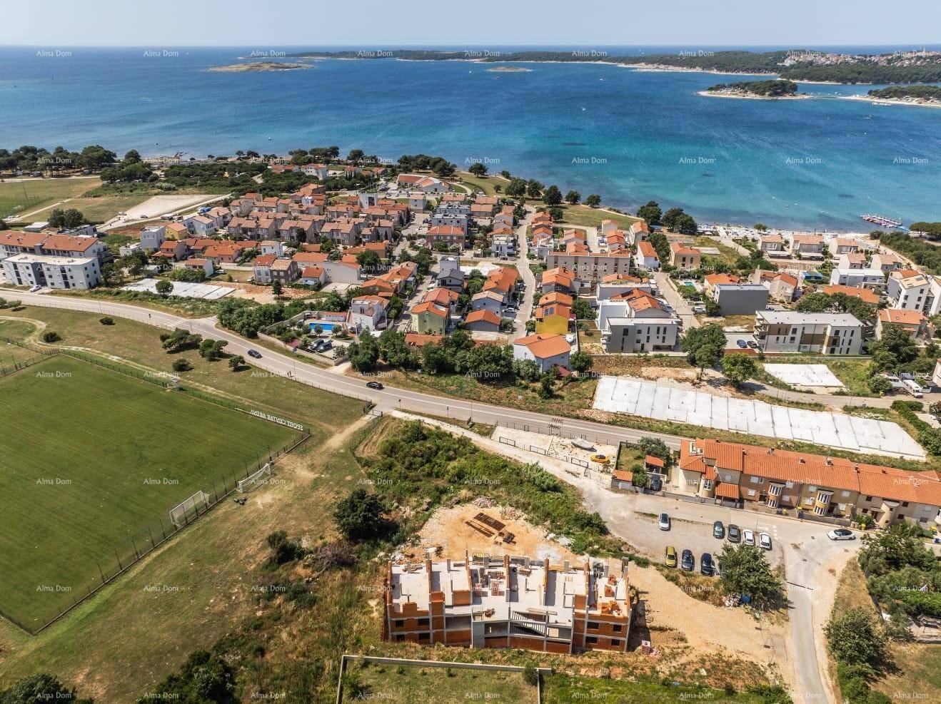Übersichtsaufnahme der Baustelle mit angrenzender Wohnsiedlung und Küstenlinie am Meer.