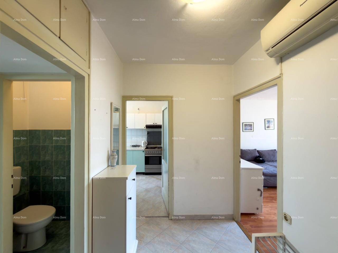 Flur mit Fliesenboden und Blick in die Küche sowie ein angrenzendes WC.