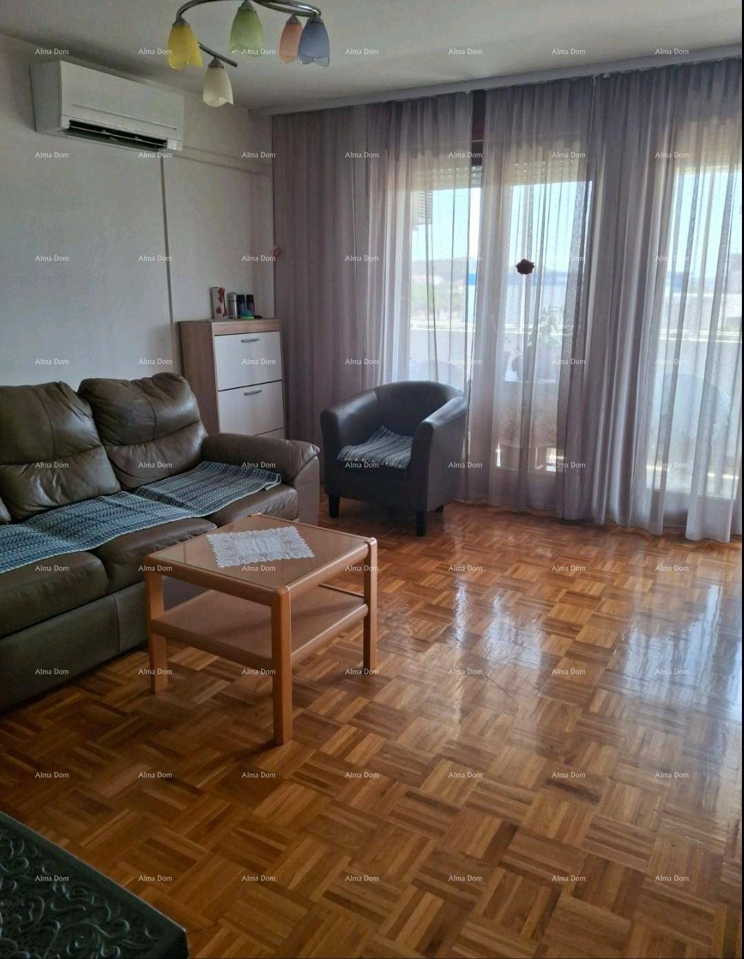 Gemütliches Wohnzimmer mit Parkettboden, bequemer Couch, Klimaanlage und großen Fenstern.