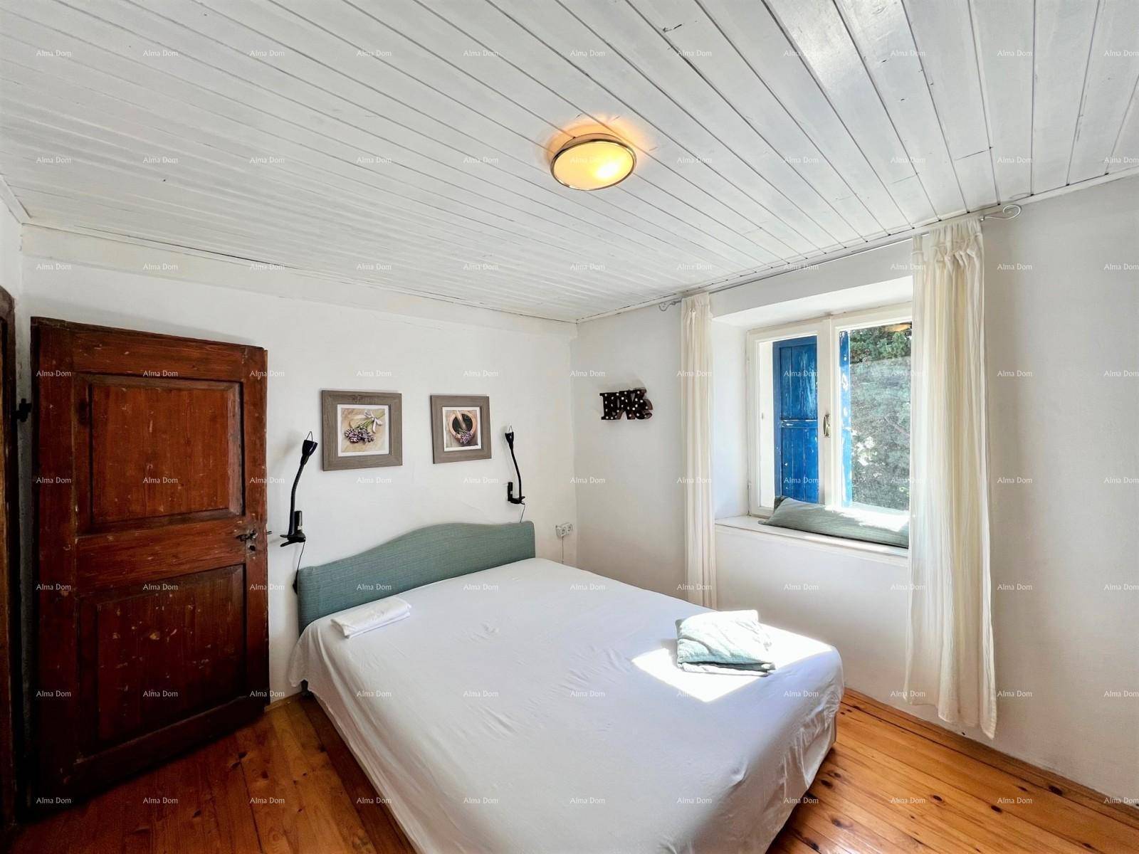 Schlafzimmer mit Holzdielenboden, weißer Holzdecke und einem Fenster mit blauen Fensterläden.