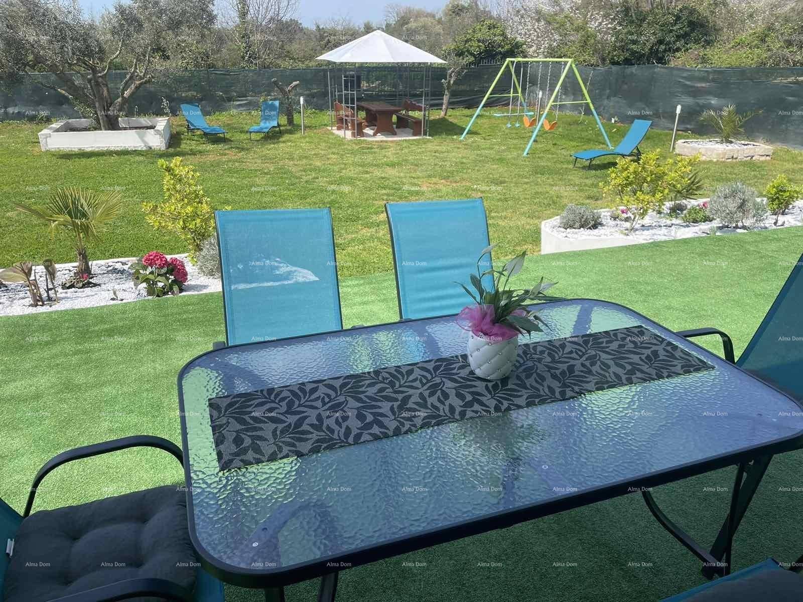 Terrasse mit Sitzgelegenheiten und Blick auf den weitläufigen Garten mit Spielplatz und Pavillon.