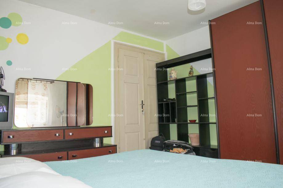 Schlafzimmer mit Kleiderschrank, Kommode und farbiger Wandgestaltung.