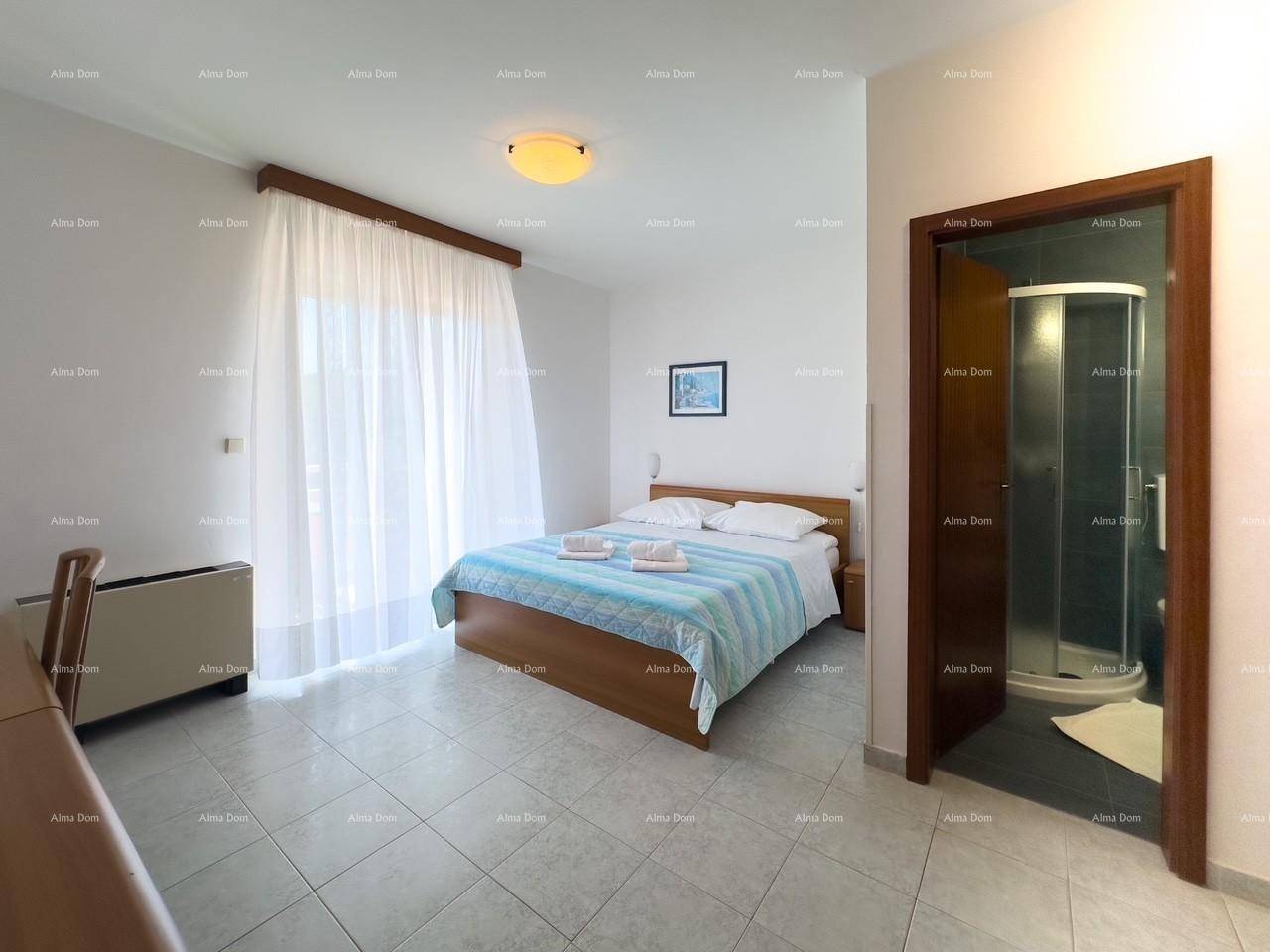Helles Schlafzimmer mit Doppelbett, Fliesenboden und Zugang zu einem Balkon, mit angrenzendem Badezimmer.