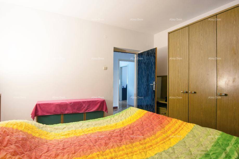 Schlafzimmer mit großem Bett, bunten Decken und einem Kleiderschrank aus Holz.