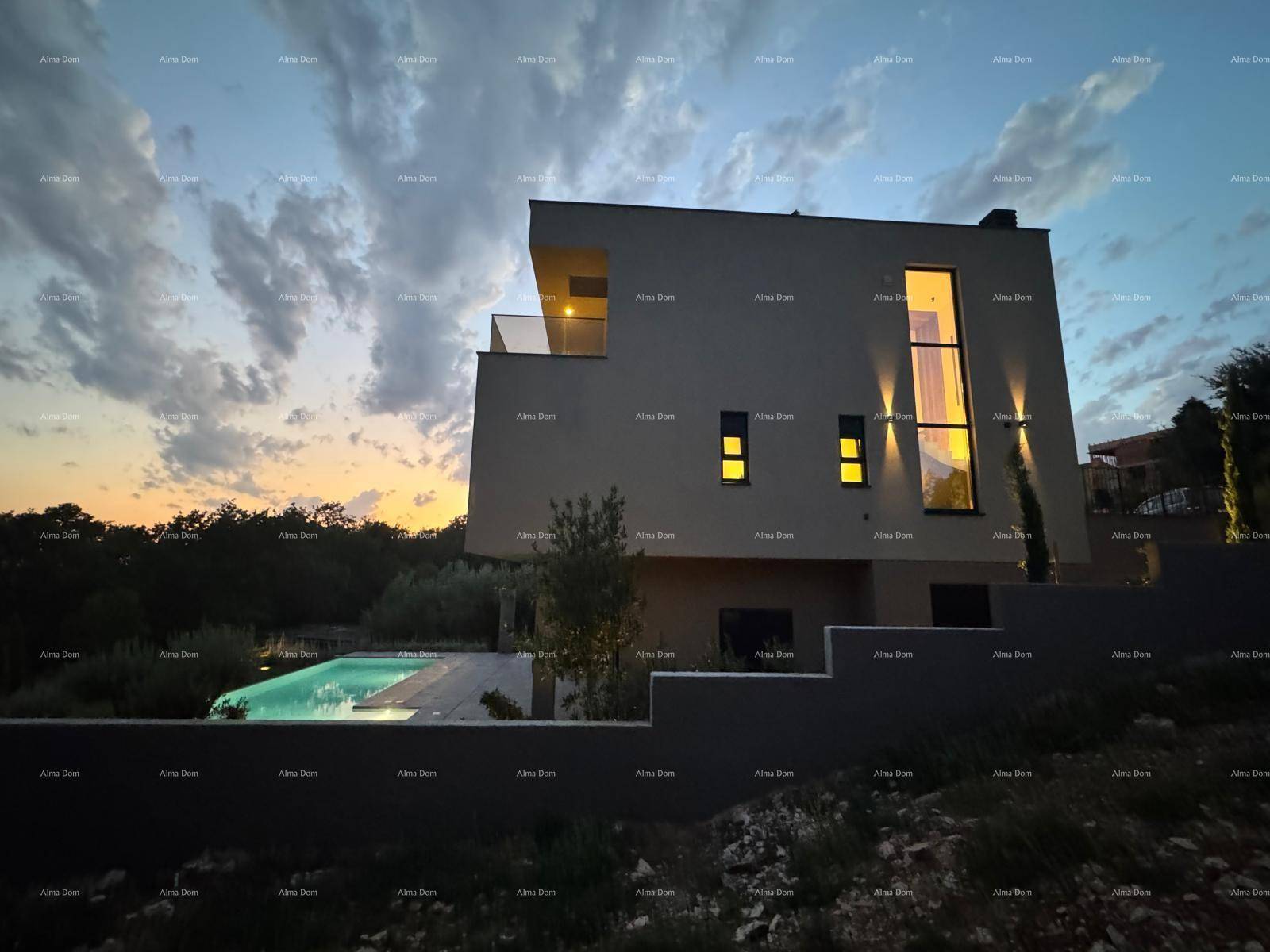 Moderne Villa mit beleuchtetem Pool und Fassade bei Sonnenuntergang, umgeben von Natur.