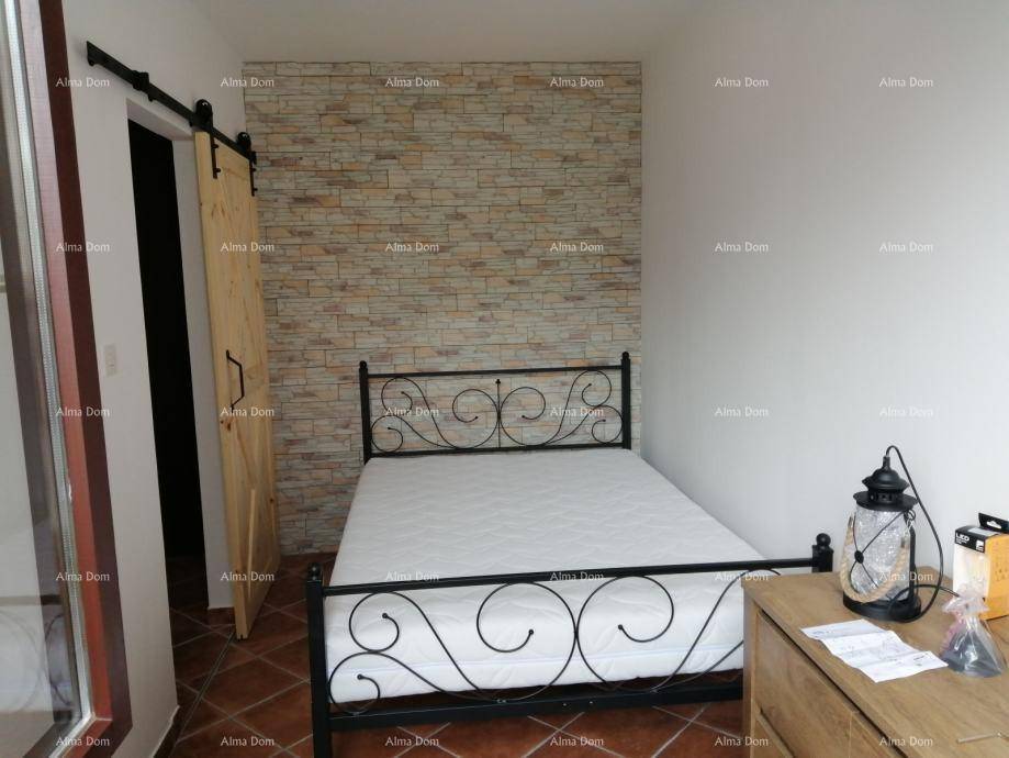 Schlafzimmer mit schmiedeeisernem Bett, rustikaler Steinwand und Schiebetür aus Holz.