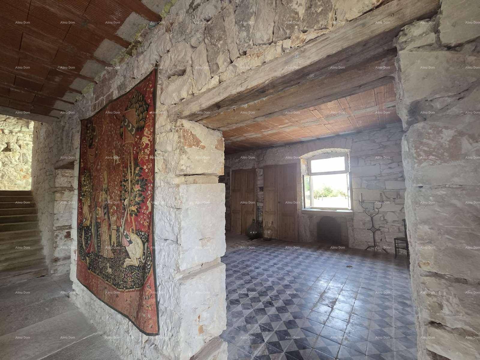 Rustikaler Raum mit freiliegenden Steinwänden, Holzbalken und einem Wandteppich, der Geschichte erzählt.