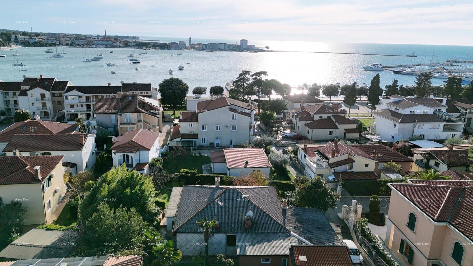 Panoramablick auf eine Küstenstadt mit Häusern, einem Hafen voller Boote und dem glitzernden Meer.