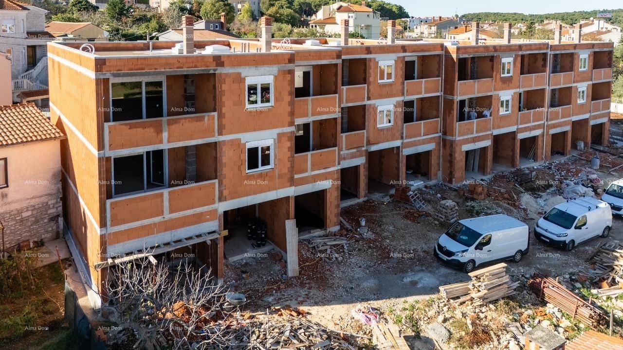Seitenansicht des im Bau befindlichen Gebäudes mit sichtbaren Ziegelwänden und Baustellenfahrzeugen.