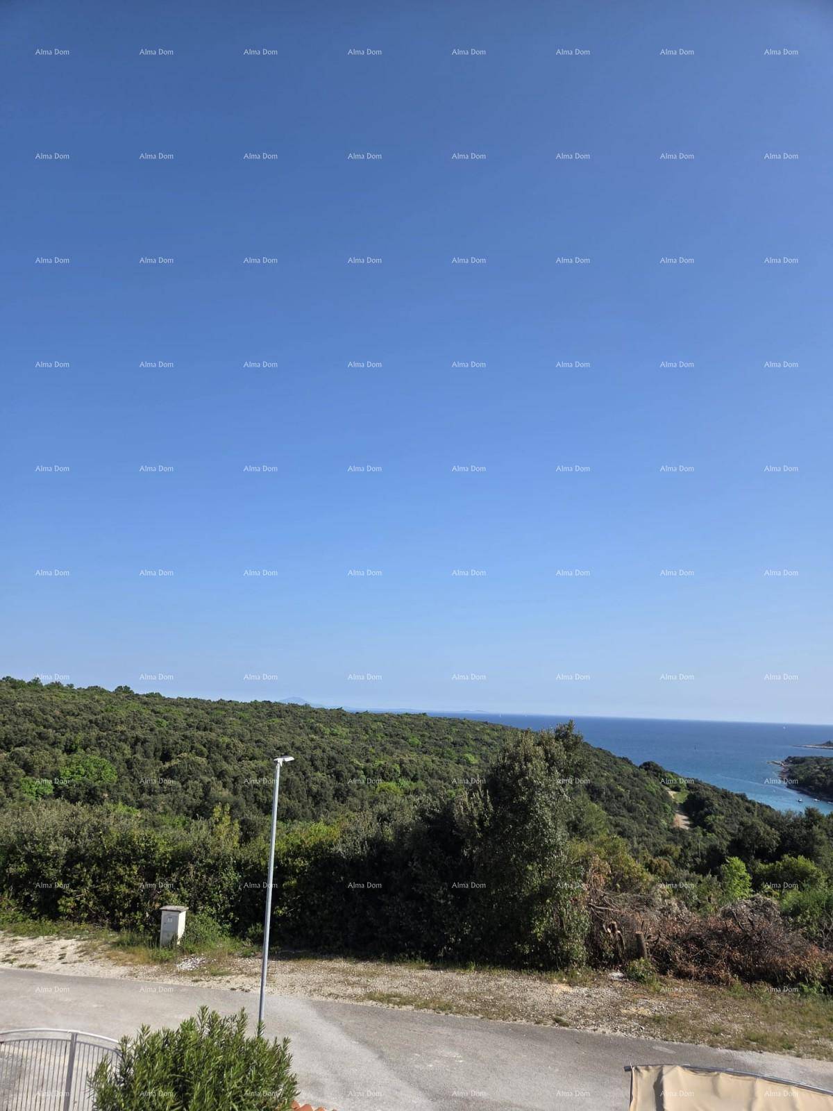 Weitläufiger Blick auf die grüne Landschaft und das Meer unter blauem Himmel.
