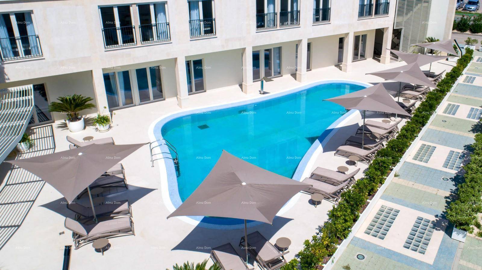 Außenansicht des Gebäudes mit großem Poolbereich, Sonnenliegen und Sonnenschirmen.