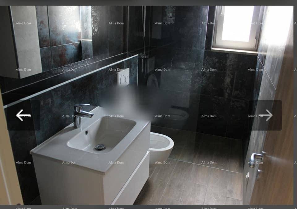 Modernes Badezimmer mit dunklen Fliesen, Einzelwaschbecken und Fenster für Tageslicht.