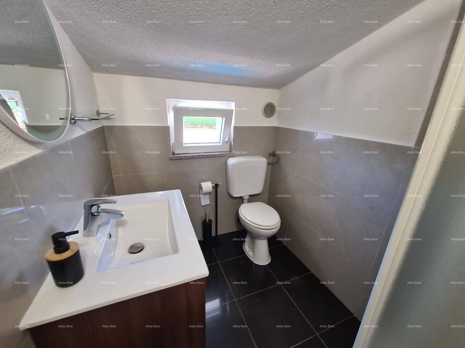 Badezimmer mit Waschbecken, Toilette und Fenster, das für natürliche Belüftung sorgt.