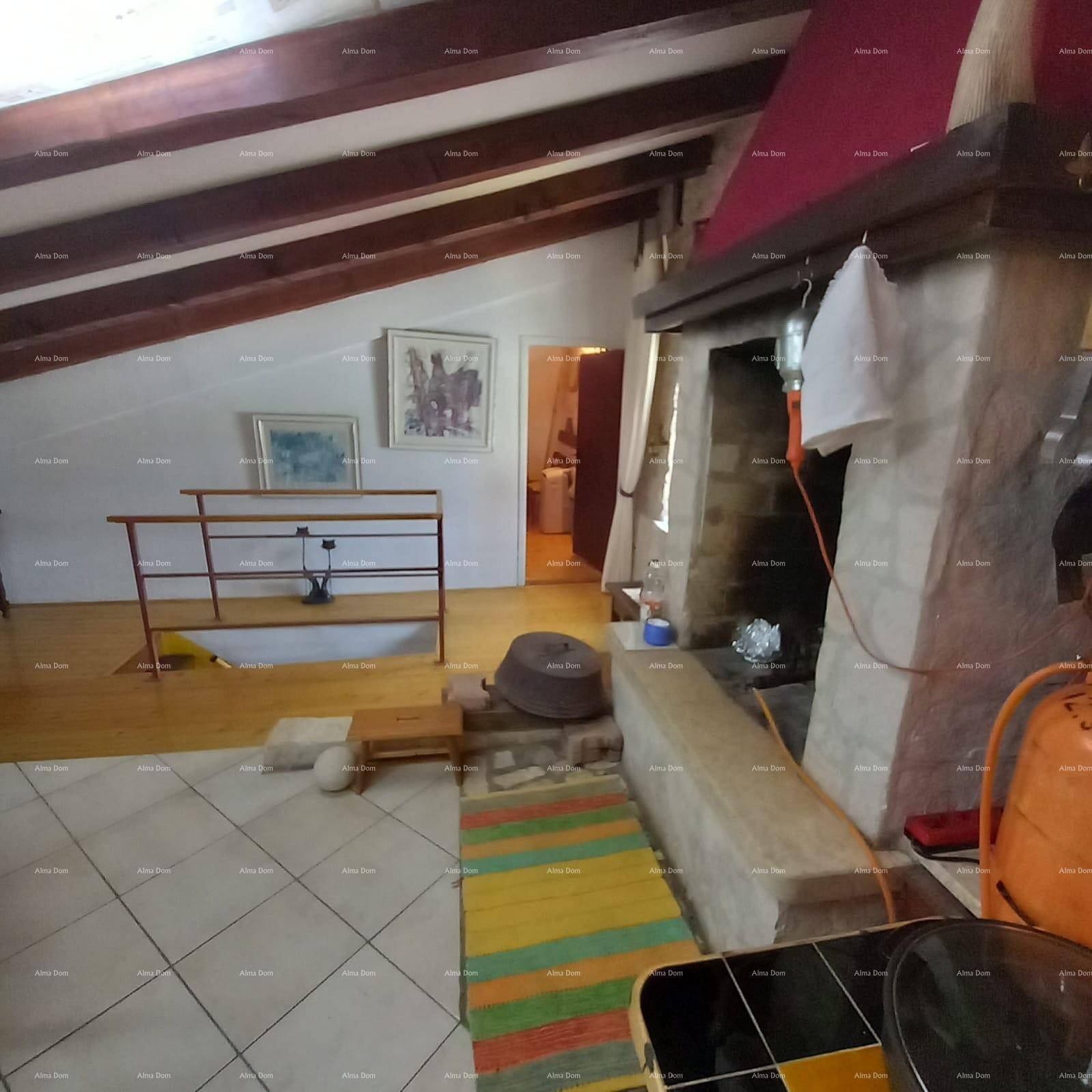 Offener Wohnbereich mit Kamin, Fliesenboden und Zugang zu einem erhöhten Holzbereich.