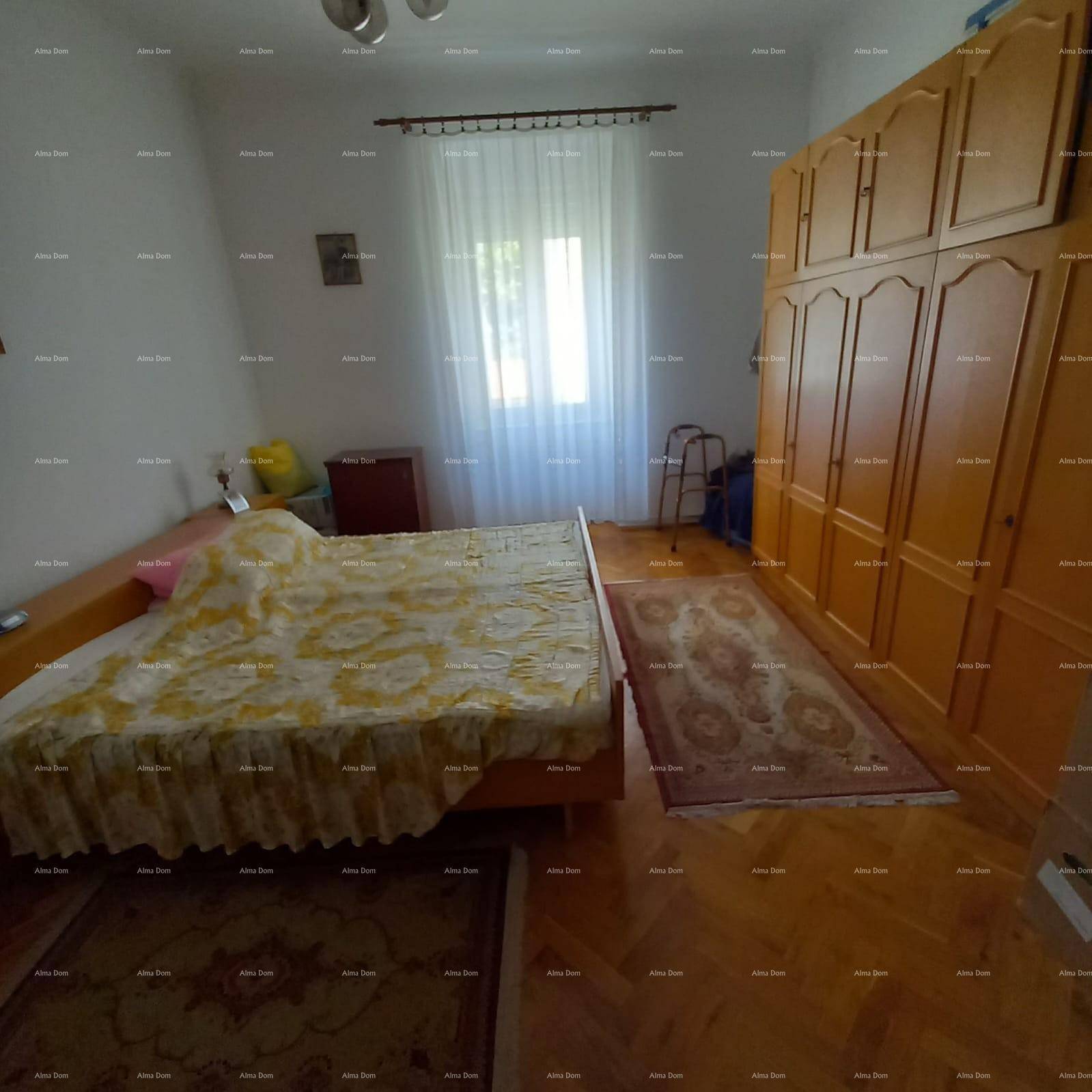 Helles Schlafzimmer mit Holzboden, großem Kleiderschrank und Fenster.