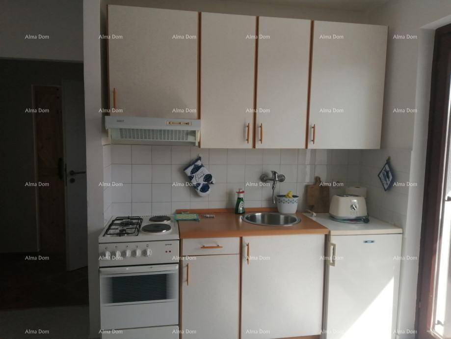 Kompakte Küchenzeile mit weißen Schränken, Gasherd und Spüle, ideal für kleine Wohnungen.