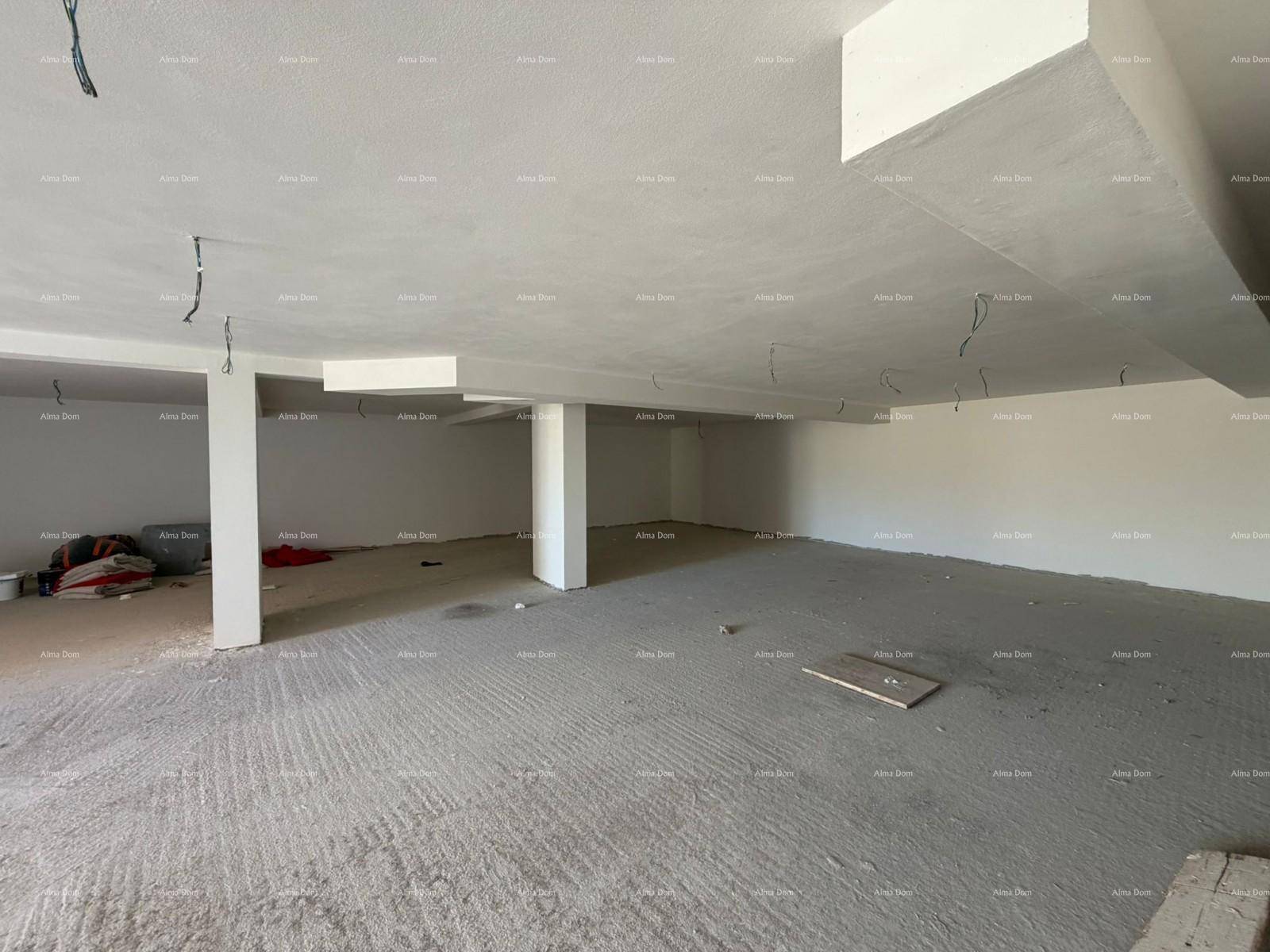 Geräumiger Rohbau-Bereich mit Betonboden und sichtbaren Installationen an der Decke, wartet auf Fertigstellung.